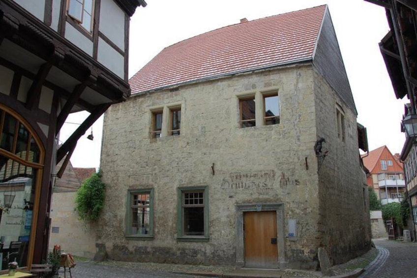 A stone building with a wooden door and windows, surrounded by cobblestone streets and traditional architecture. 3