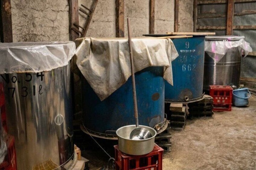 Industrial storage tanks, a metal bucket, and a ladder in a warehouse. 2