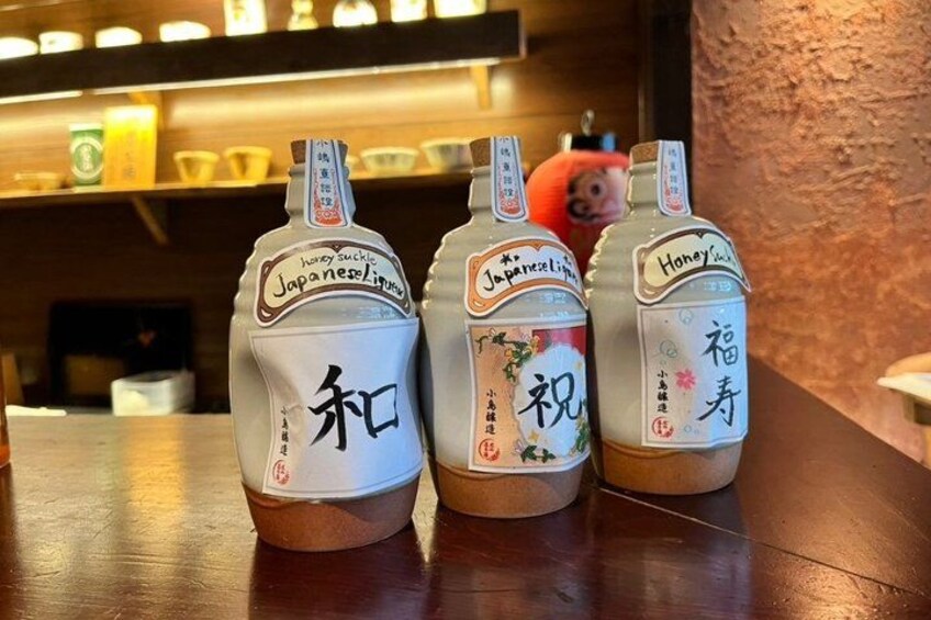 Three bottles of Japanese sake with labels, placed on a wooden surface. 1