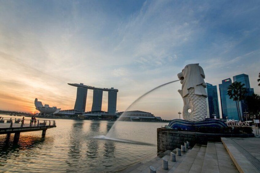A waterfront with a large statue, a modern building, and a clear sky. 2