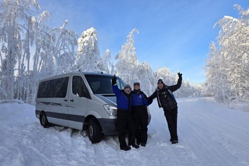 A snowy landscape with a van parked on the side of a road, surrounded by snow-covered trees. 2