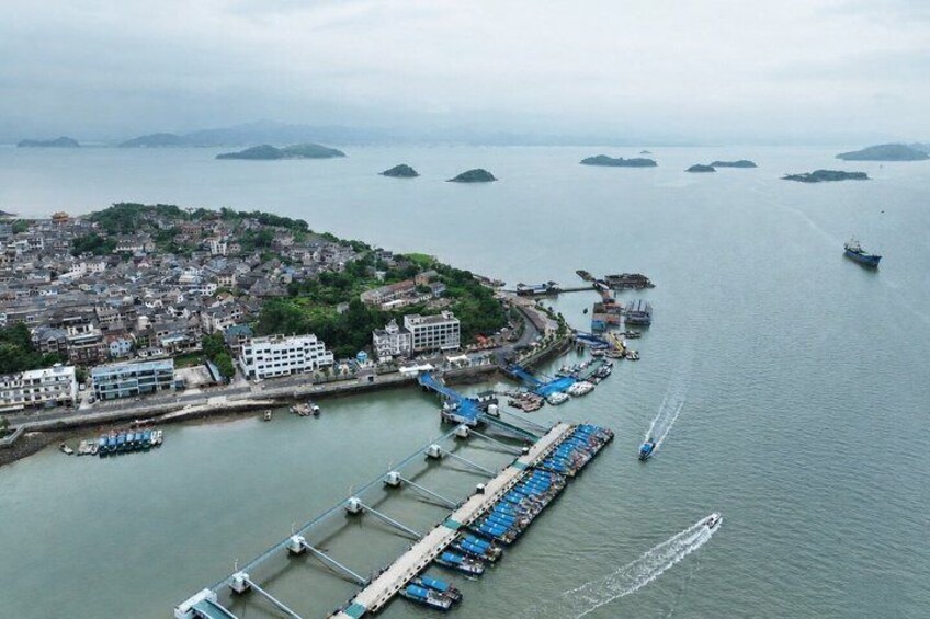 A coastal city with a dock, boats, and a mountainous backdrop. 2