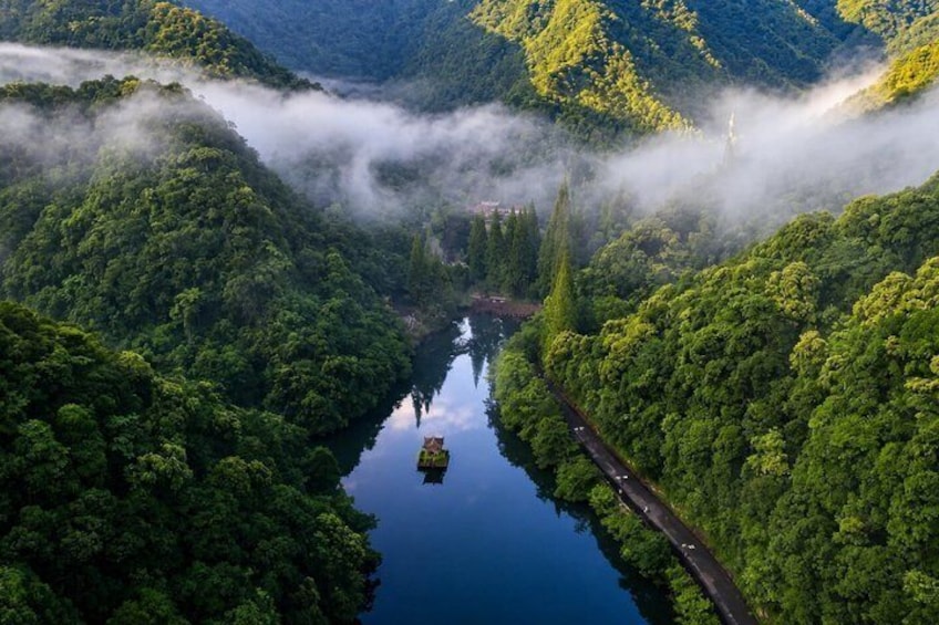 A river winding through a forested valley with a road alongside it. 1