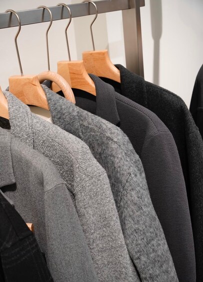 A rack of sweaters in various shades of gray and black. 4