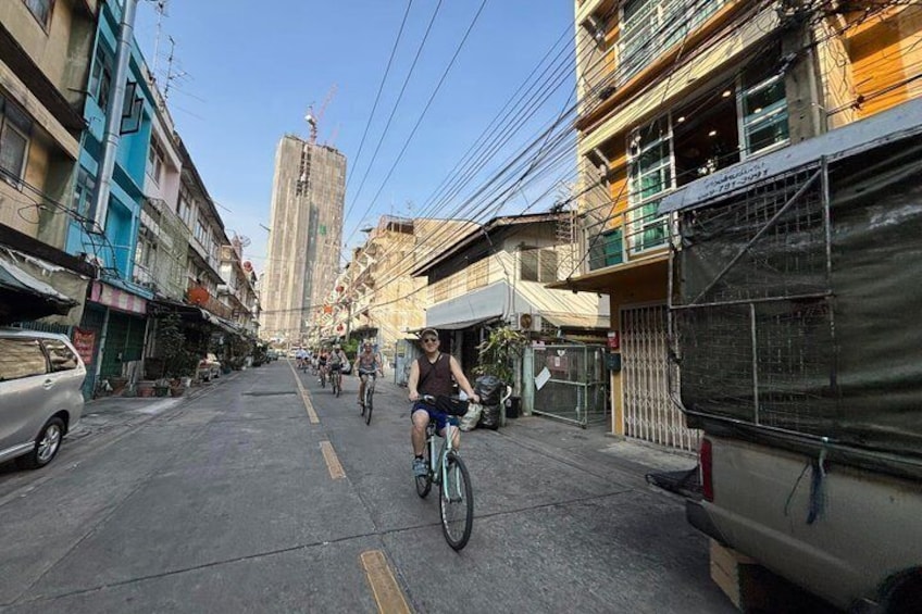 A street with buildings, a cyclist, and a parked car. 5