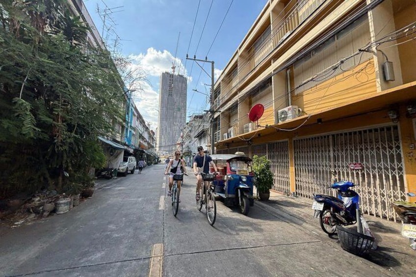 A street with cyclists, parked motorcycles, and a tall building in the background. 4