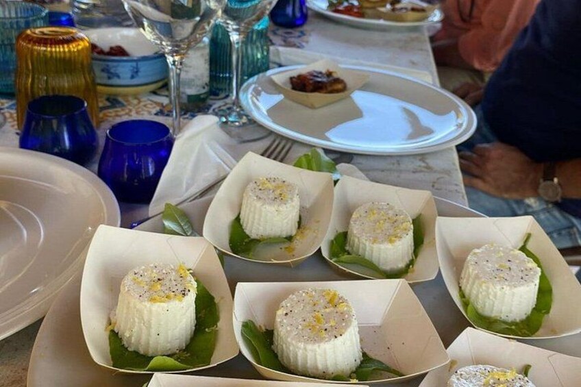 A table with several white, round desserts on banana leaves. 5