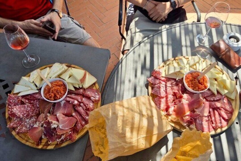 Two tables with charcuterie boards, wine glasses, and a person in the background. 2