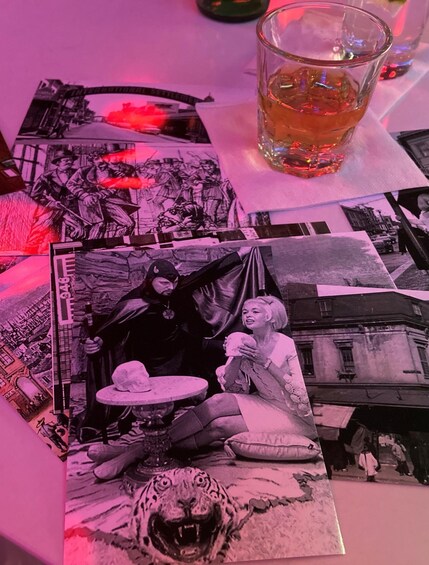 A table with various photographs, a glass of amber liquid, and a book with a tiger illustration. 2