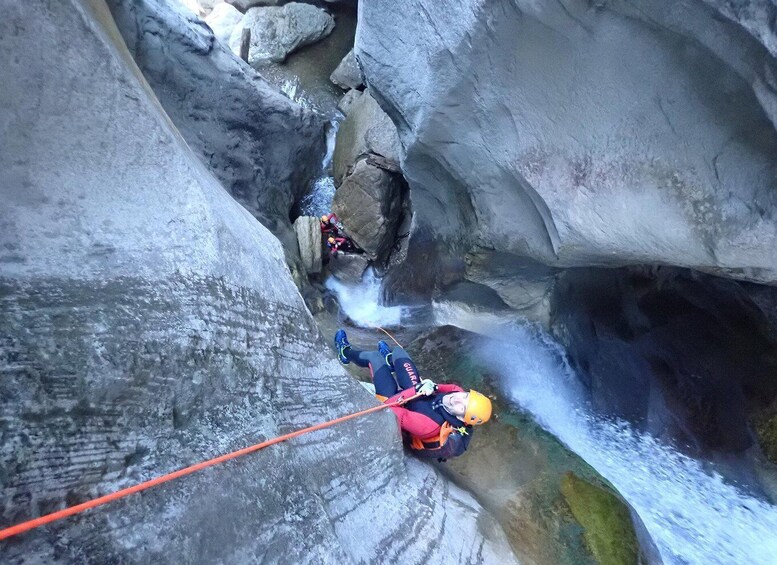 A person rappelling down a rocky cliff with a rope. 3