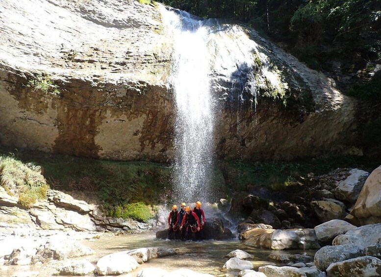 A waterfall in a rocky gorge with a group of people standing at the base. 2