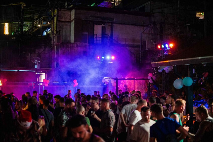 A crowded indoor event with a stage and smoke effects. 2