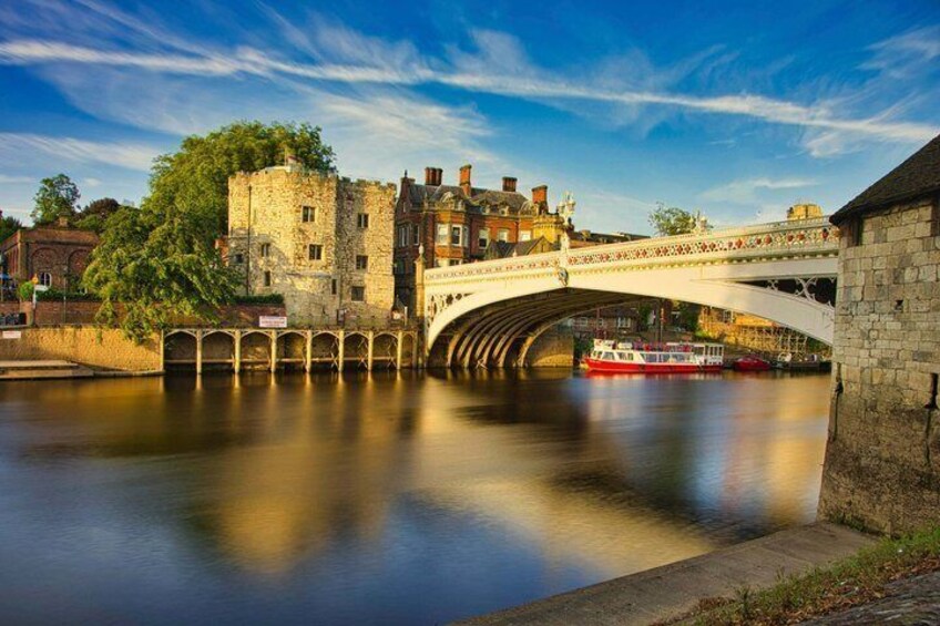 A stone bridge over a river, a red boat, and historic buildings. 3