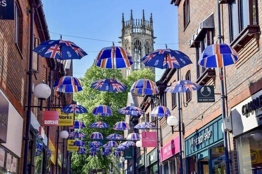A street with umbrellas, shops, and a church tower. 4