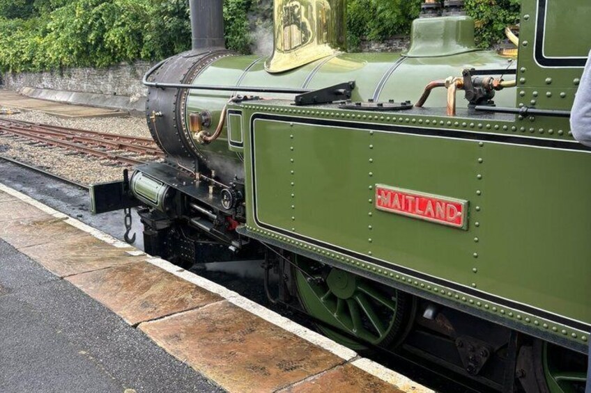 A green steam locomotive with the name 'Maitland' on its side, parked on a railway track. 4