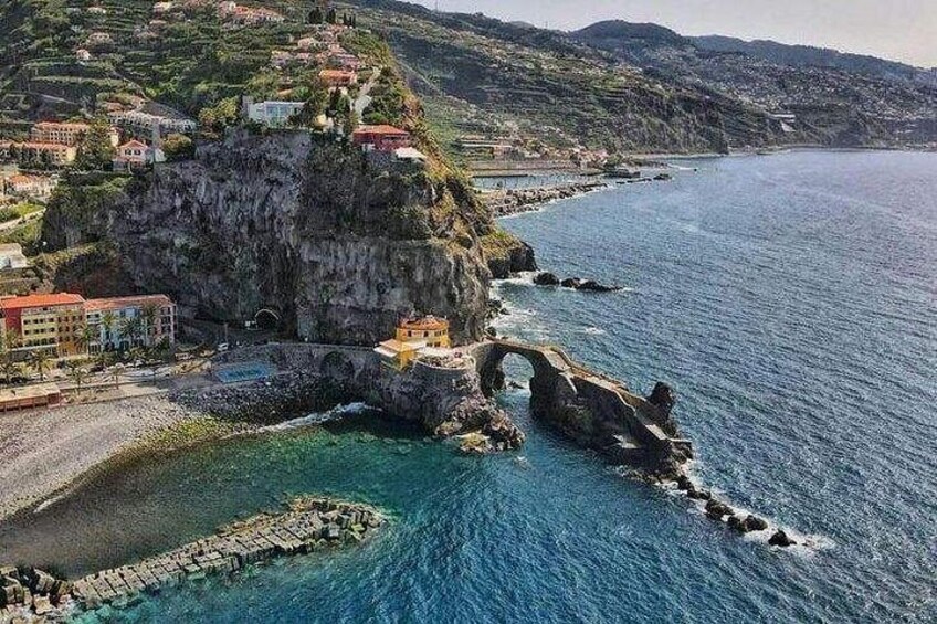 A coastal town with a prominent rock formation and a bridge. 4