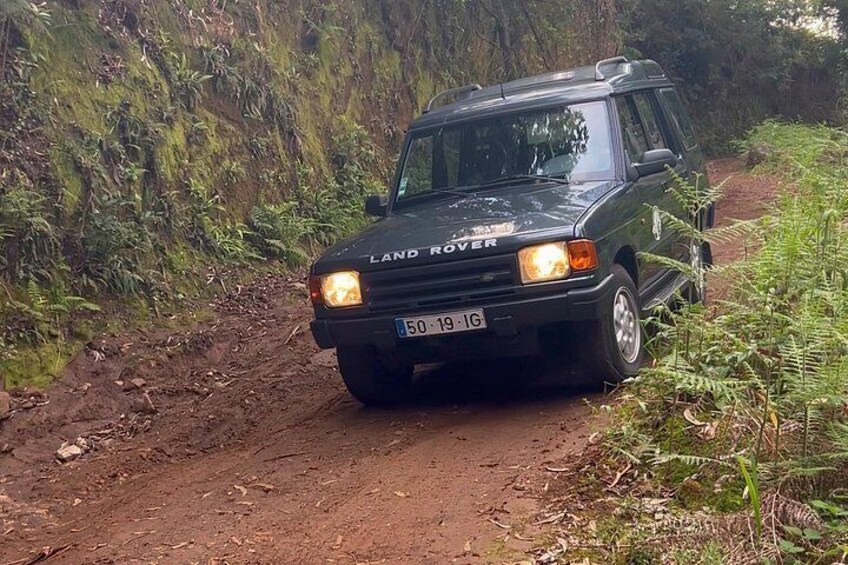A black Land Rover on a dirt road surrounded by greenery. 2