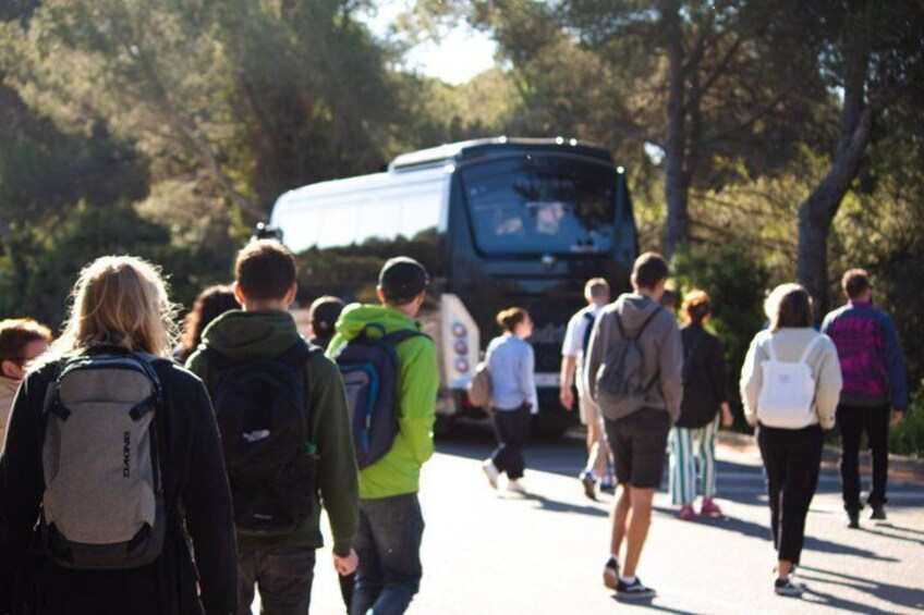 A group of people walking on a road with a bus in the background. 4