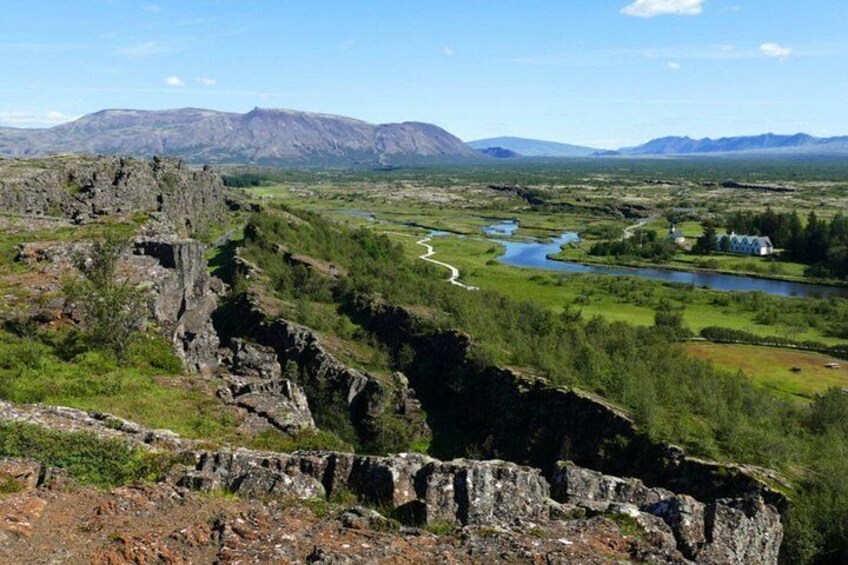 A rugged landscape with a river, a rocky outcrop, and distant mountains. 1