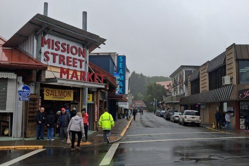 A street with shops, including a 'Mission Street Market' and a 'Salmon' sign, and a pedestrian crossing. 5