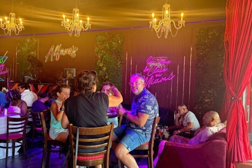 A restaurant interior with wooden chairs, tables, and a neon sign. 1