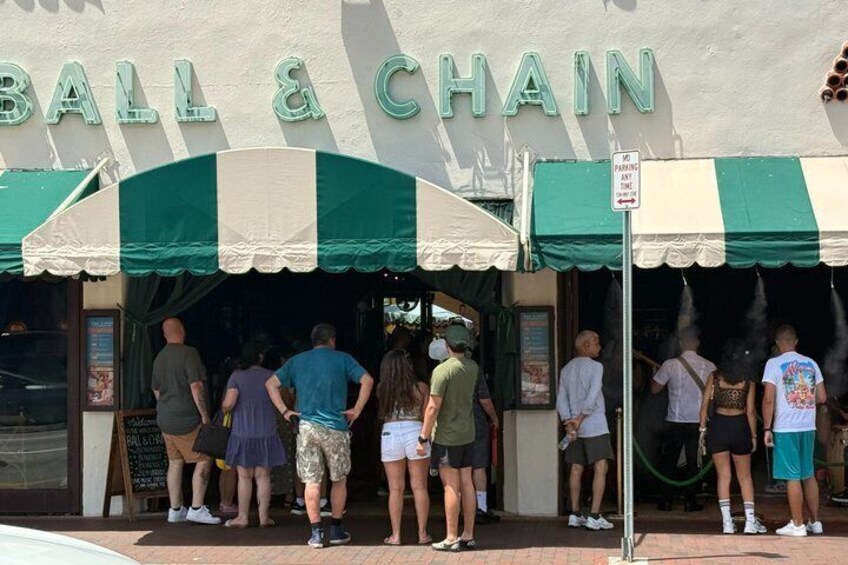 A BALL & CHAIN restaurant with a green and white striped awning. 4