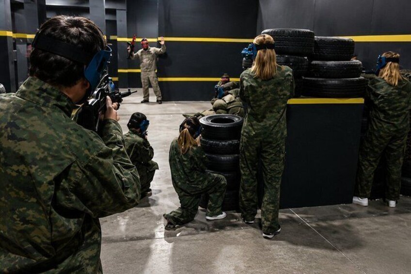Soldiers in camouflage uniforms engaged in a training exercise with paintball guns, aiming at targets. 4