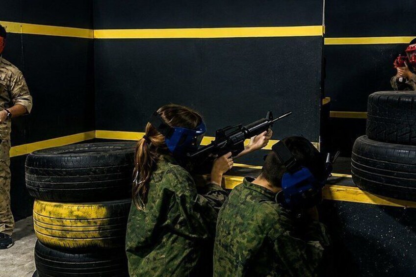 People in military uniforms aiming paintball guns at targets. 2