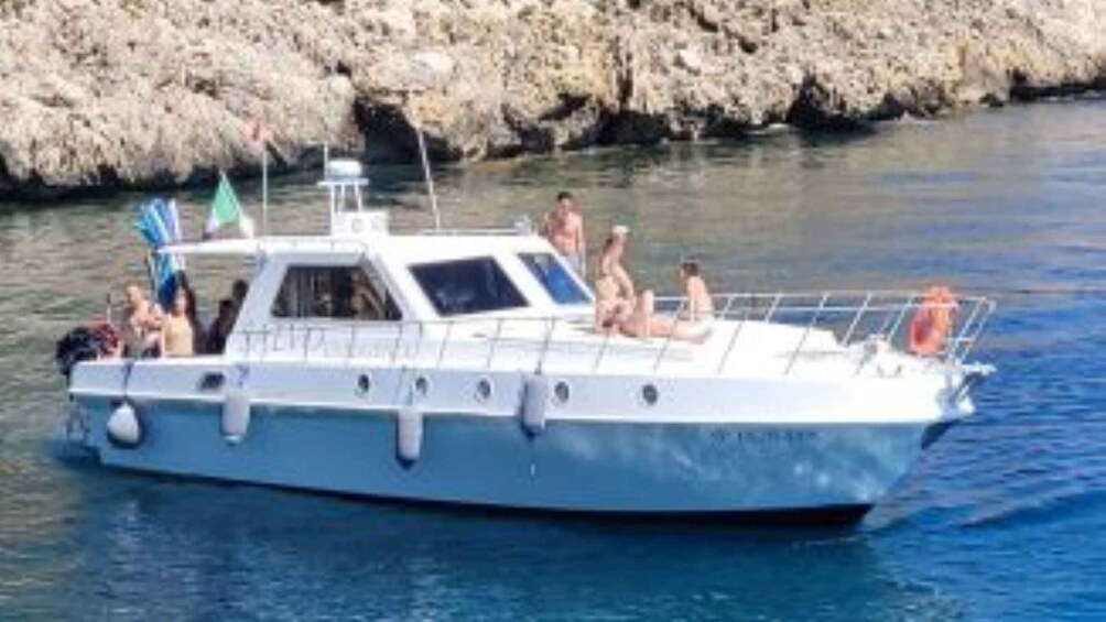 A boat with people on board, a rocky shoreline in the background, and calm water. 3