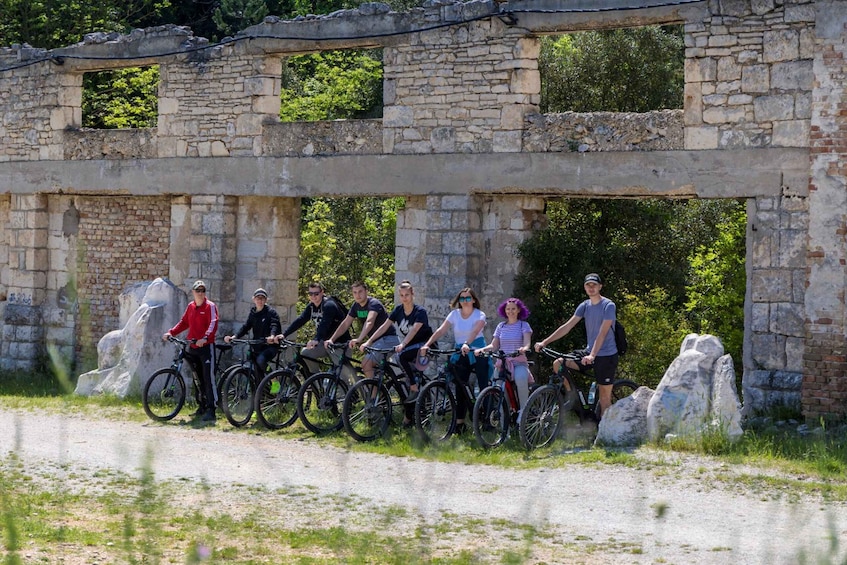 A group of cyclists posing in front of an ancient stone structure. 4