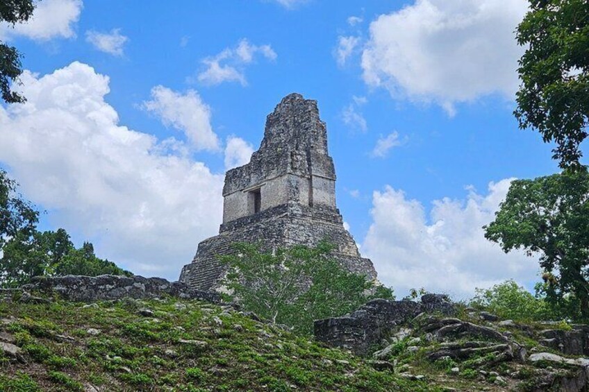 A large ancient pyramid-like structure with a flat top, surrounded by lush greenery and trees. 4