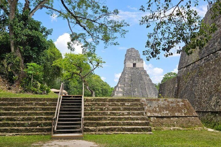 A stone staircase leading to a pyramid-like structure surrounded by lush greenery. 5