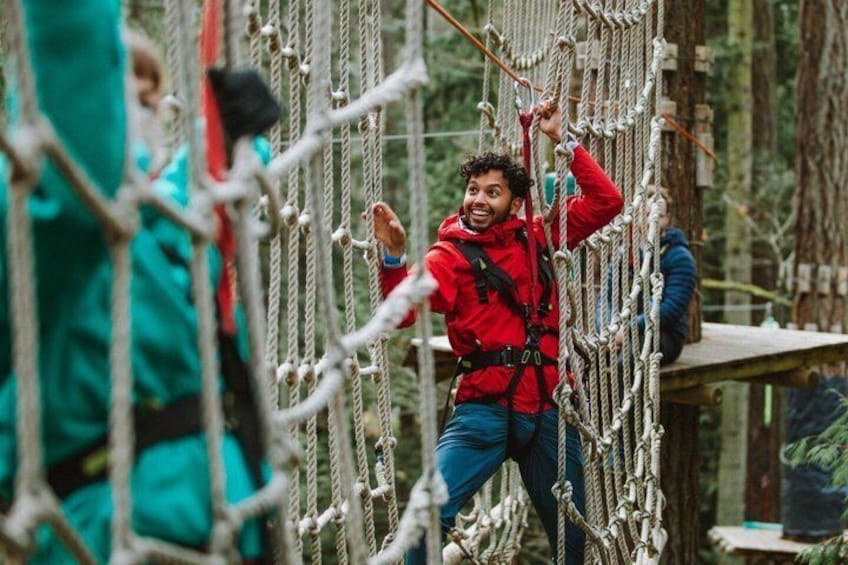 A person navigating a rope bridge in a forested area. 4
