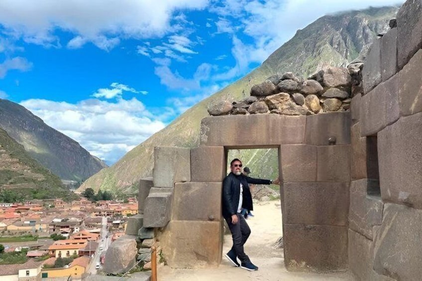 A person standing in front of a stone structure with a mountainous landscape in the background. 3