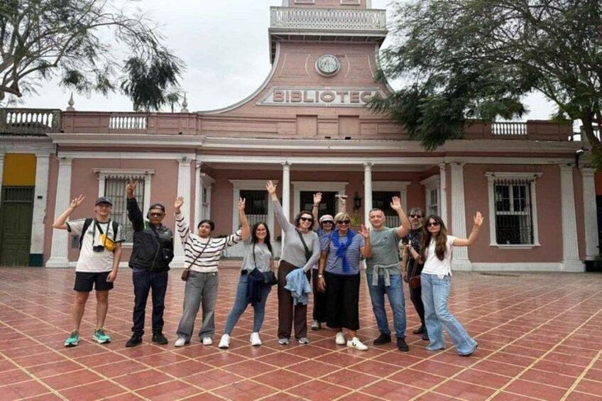 A group of people posing in front of a building with columns and a clock. 5