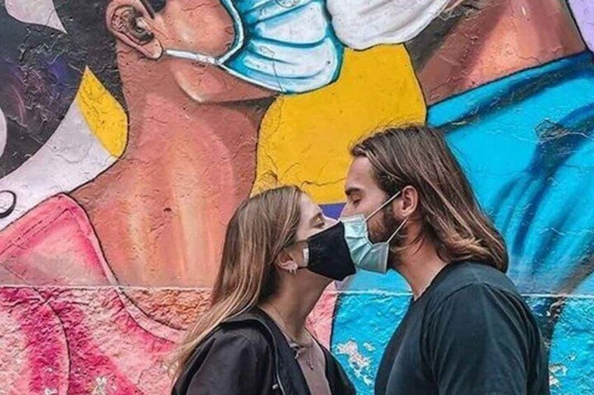 A couple standing in front of a colorful mural. 5