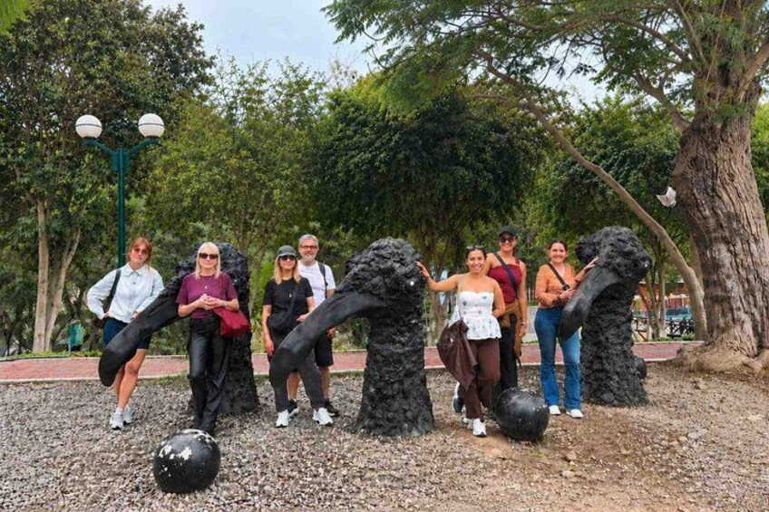 A group of people playing soccer in a park with trees and a statue in the background. 3