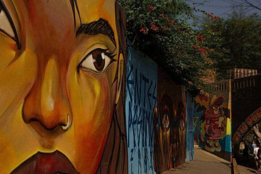 A street with colorful graffiti and a mural of a face. 2