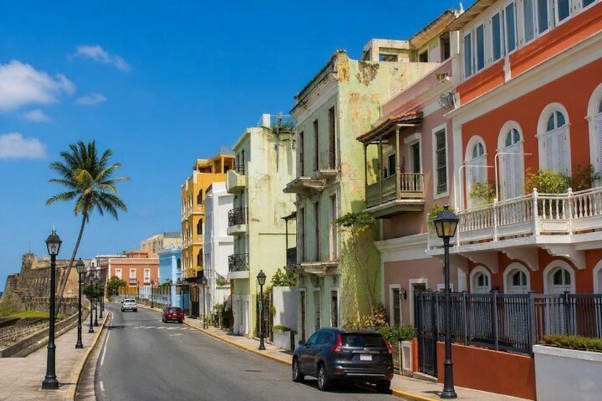 A street lined with colorful buildings, a palm tree, and a parked car. 5