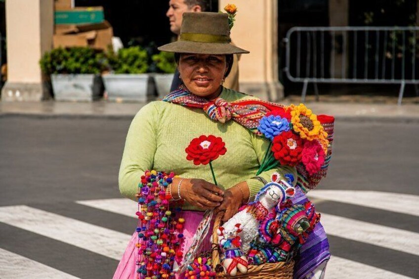 A person with a hat and colorful attire, holding a basket with flowers and a stuffed toy. 2
