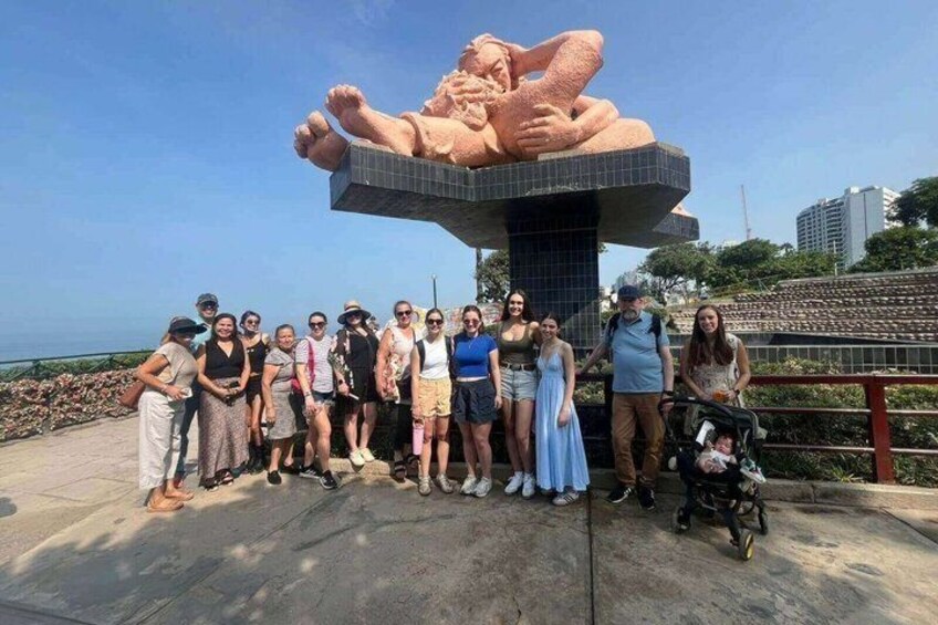 A group of people posing in front of a large sculpture of a reclining figure. 4