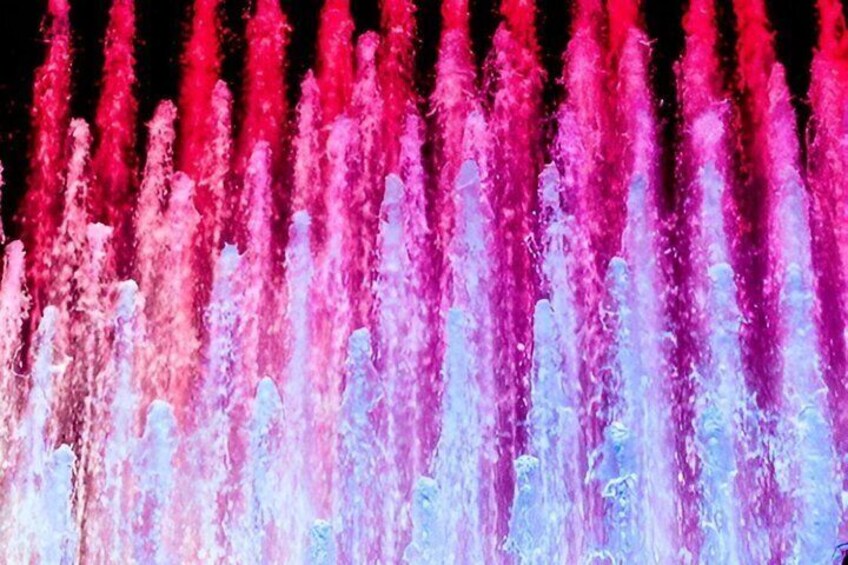 A water fountain with multiple streams of water in shades of pink and blue. 4