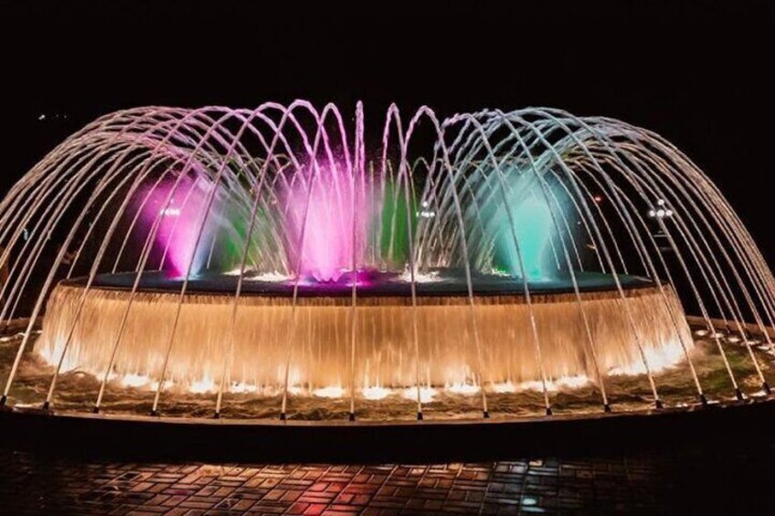 A nighttime illuminated fountain with water jets and colorful lights. 1