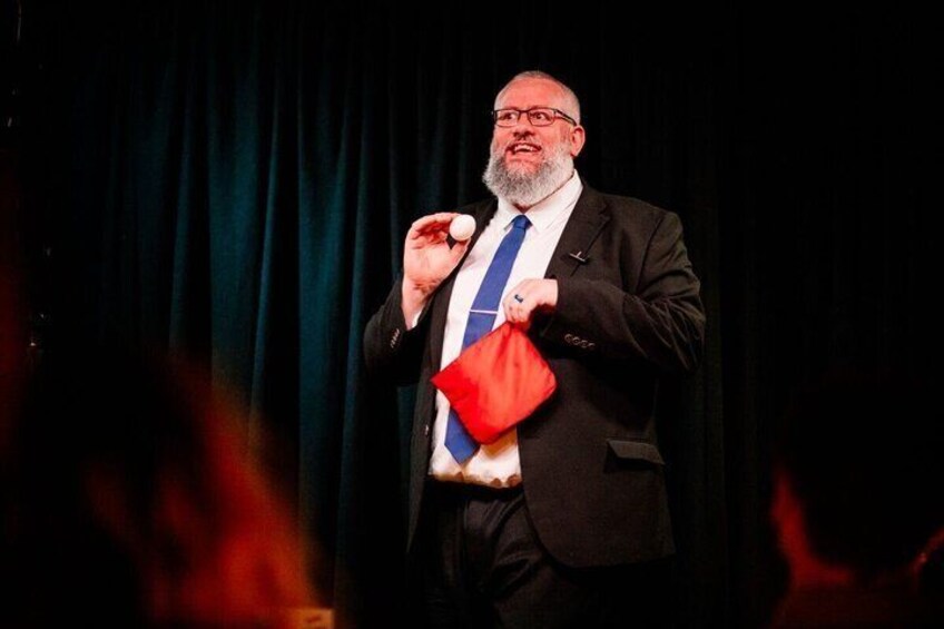 A person in a suit holding a red object and a white object. 5