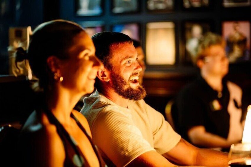A person with a beard and a woman with long hair sitting at a table in a dimly lit bar. 1