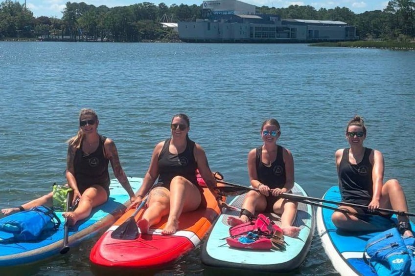 Four people on paddleboards on a calm lake with a building in the background. 4