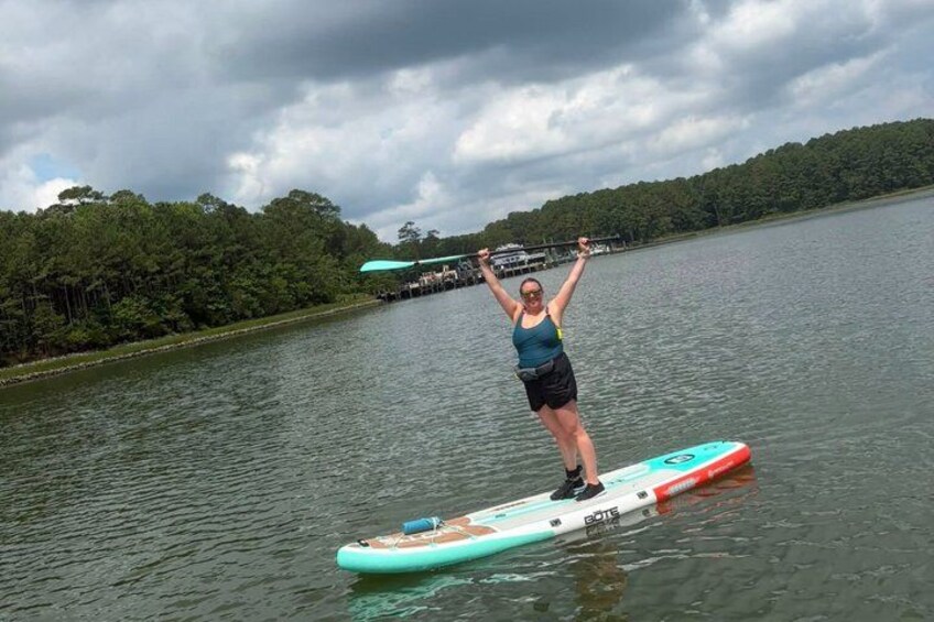A person paddleboarding on a calm lake with trees in the background. 2