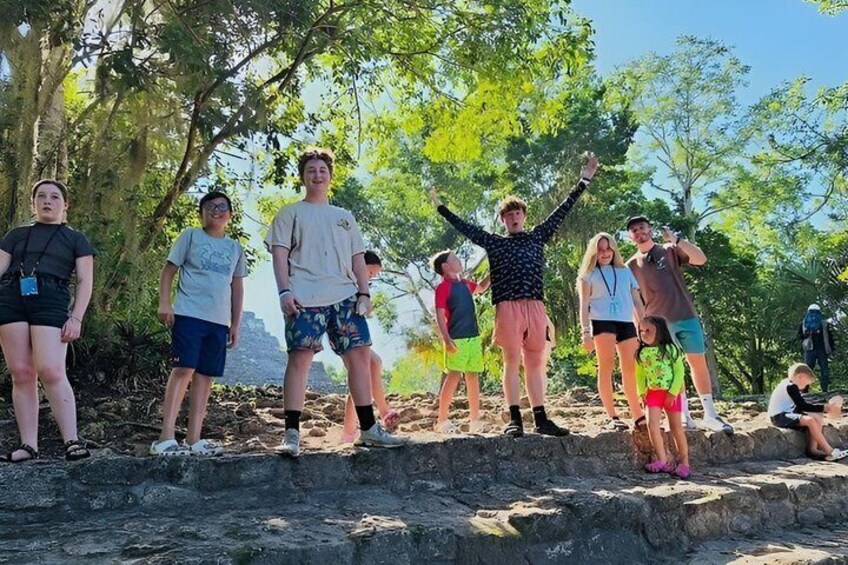 A group of people standing on a rocky ledge with trees in the background. 4
