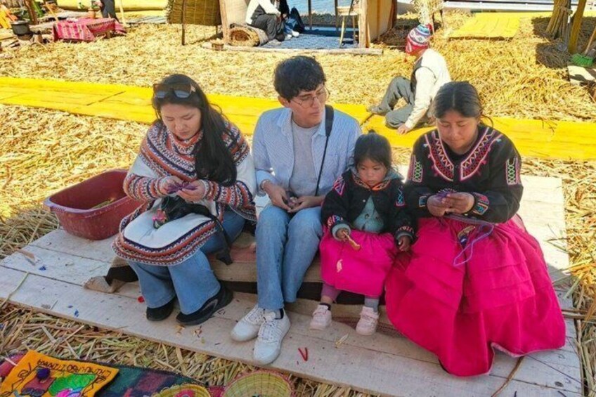 A group of people sitting on a mat outdoors, surrounded by straw and hay. 4