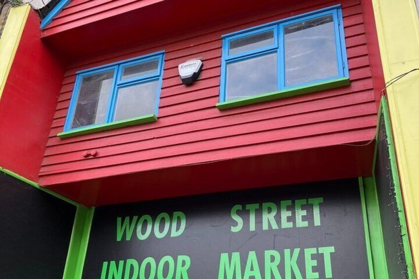 A red building with green trim and blue-framed windows. The sign reads 'WOOD STREET INDOOR MARKET'. 3